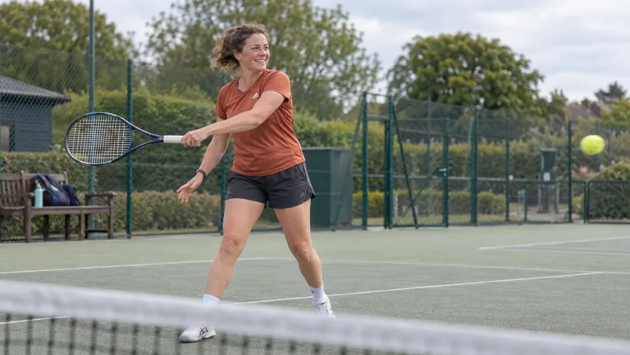 A woman playing a forehand on an outdoor tennis court